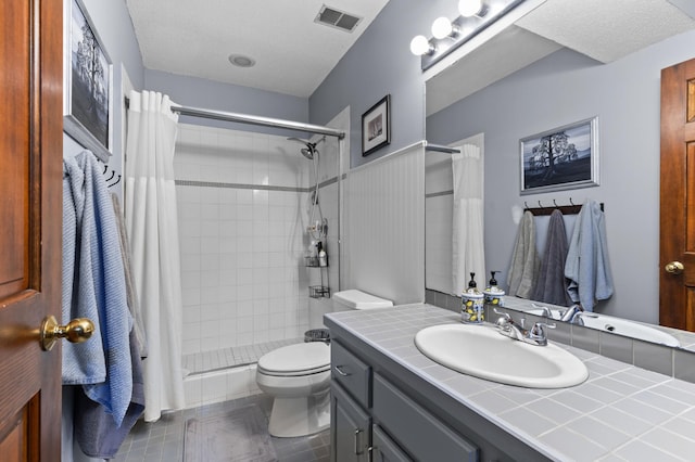 full bath featuring toilet, a tile shower, and vanity
