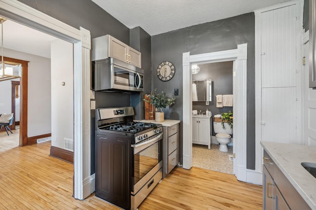 kitchen featuring stainless steel appliances, light wood-style flooring, and visible vents