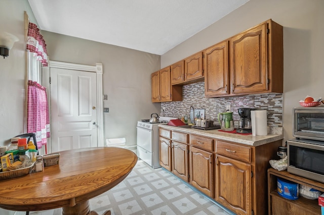 kitchen with light floors, light countertops, stainless steel microwave, tasteful backsplash, and electric stove