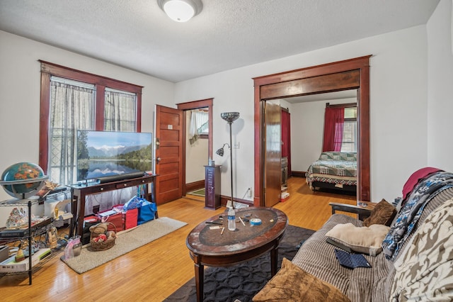 living room featuring baseboards, light wood finished floors, and a textured ceiling