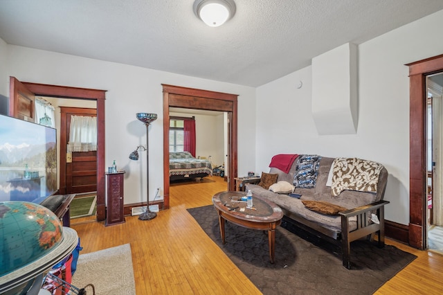 living room featuring baseboards, a textured ceiling, and wood finished floors
