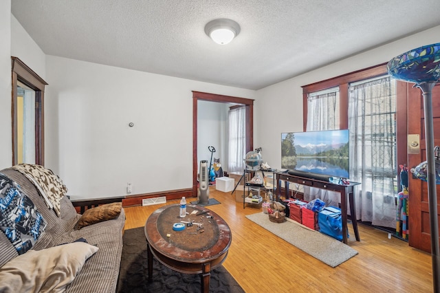 living room with baseboards, a textured ceiling, wood finished floors, and visible vents