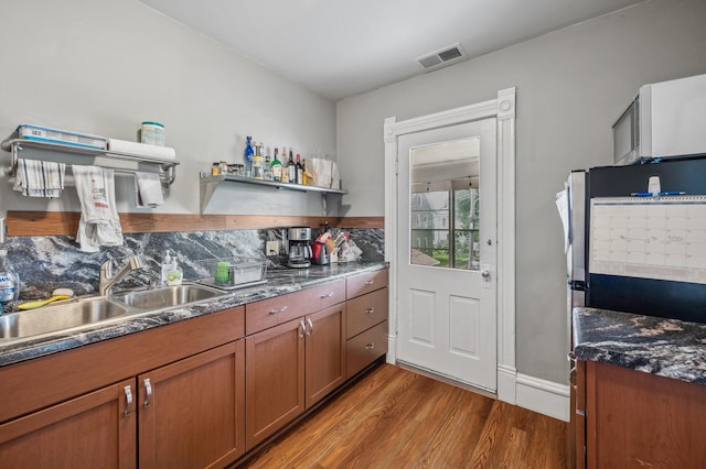 kitchen with visible vents, open shelves, wood finished floors, brown cabinets, and a sink