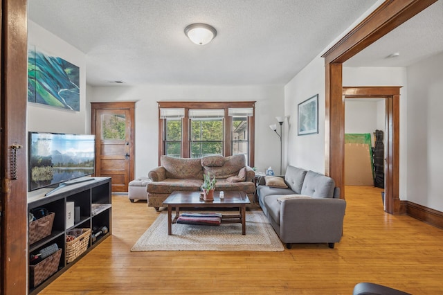 living room with light wood-type flooring and a textured ceiling