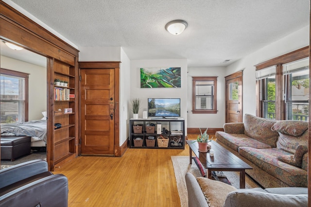 living area featuring baseboards, a textured ceiling, and light wood-style flooring