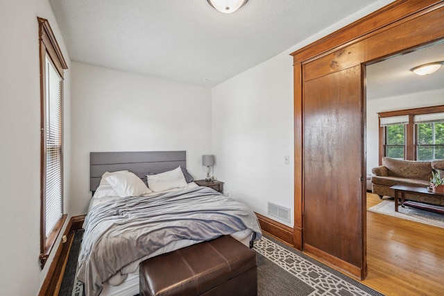 bedroom featuring baseboards, visible vents, and wood finished floors