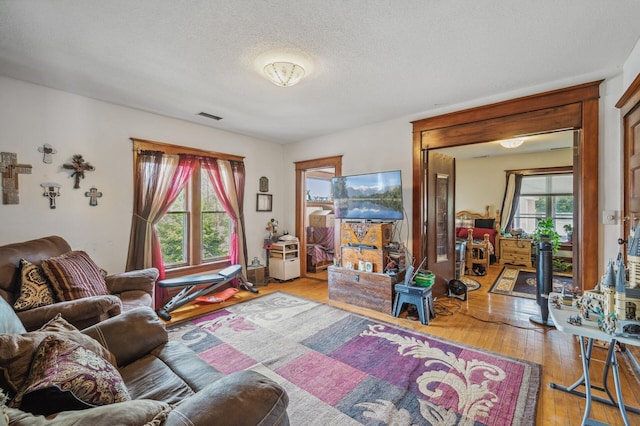 living room featuring a textured ceiling, visible vents, and hardwood / wood-style floors