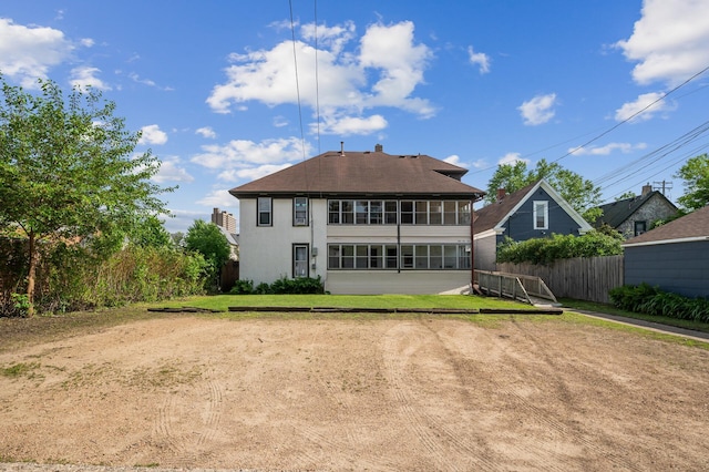 rear view of house with a lawn, fence, a shingled roof, and stucco siding