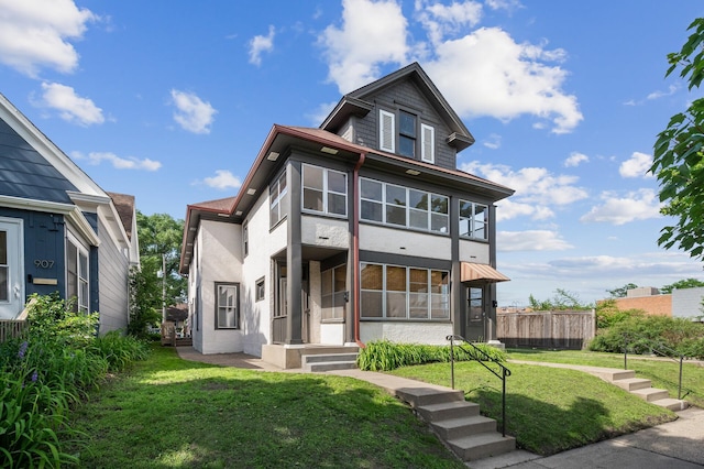 american foursquare style home with fence, a front lawn, and stucco siding