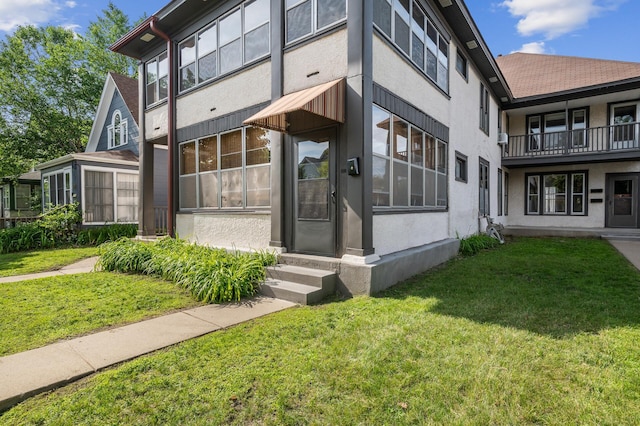 exterior space with entry steps, stucco siding, and a lawn