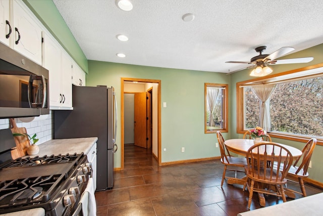 kitchen featuring decorative backsplash, a textured ceiling, appliances with stainless steel finishes, baseboards, and white cabinetry