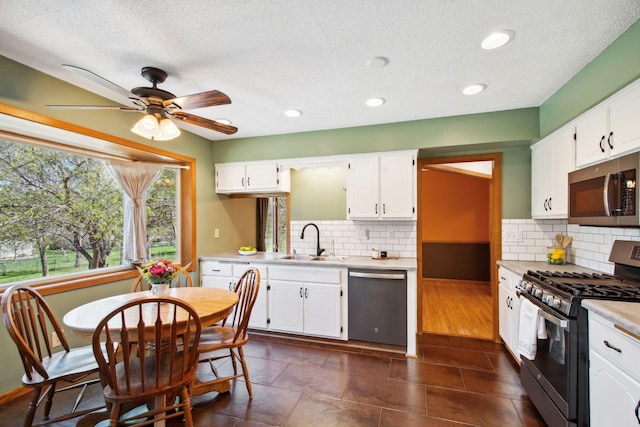 kitchen featuring light countertops, a textured ceiling, white cabinets, a sink, and stainless steel appliances