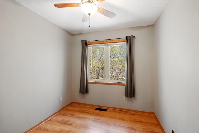 empty room with a ceiling fan, baseboards, visible vents, and light wood-style floors