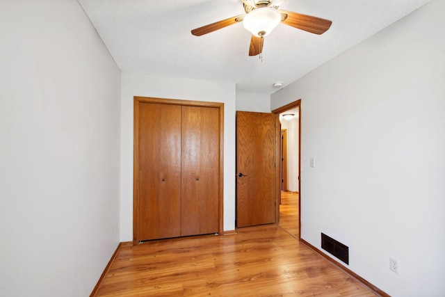 unfurnished bedroom featuring visible vents, a ceiling fan, light wood finished floors, and a closet