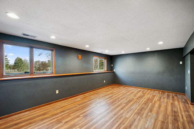 empty room featuring visible vents, recessed lighting, baseboards, and wood finished floors