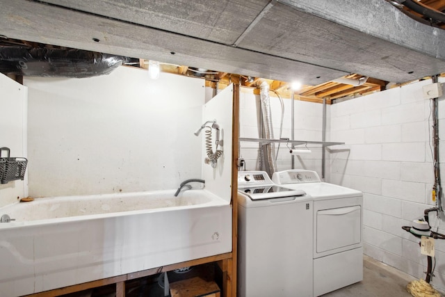 clothes washing area featuring concrete block wall, laundry area, and washer and clothes dryer