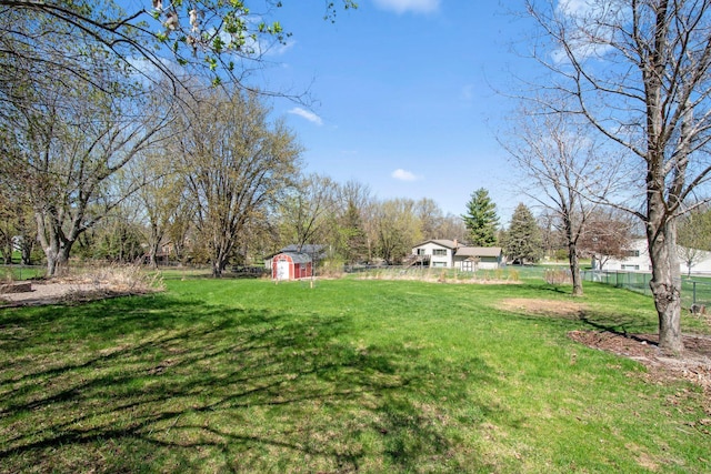 view of yard featuring a storage unit, fence, and an outbuilding