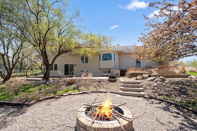 rear view of house featuring a patio, a shingled roof, and an outdoor fire pit