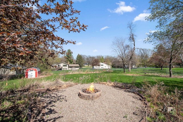 view of yard featuring an outdoor fire pit, a shed, and an outbuilding