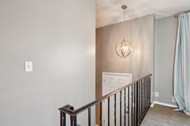 stairway with baseboards, a textured ceiling, carpet, and a notable chandelier