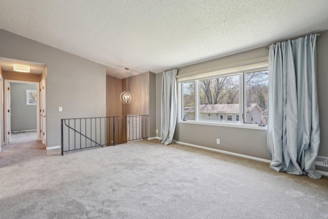 unfurnished room with carpet flooring, a textured ceiling, and baseboards