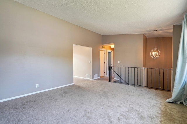 carpeted spare room with a textured ceiling, visible vents, baseboards, lofted ceiling, and an inviting chandelier