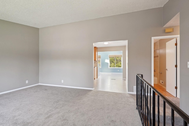 unfurnished room with carpet floors, a textured ceiling, and baseboards