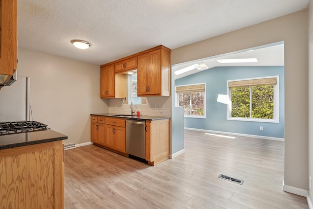 kitchen with stainless steel dishwasher, a sink, light wood-style floors, and gas cooktop