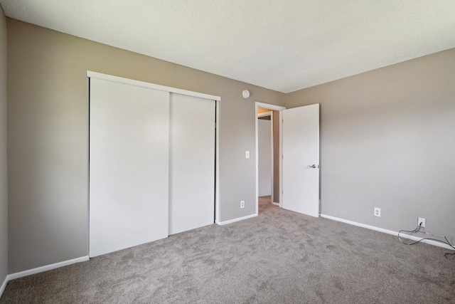 unfurnished bedroom with baseboards, carpet, and a closet
