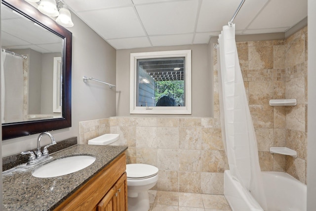 bathroom featuring vanity, toilet, tile patterned floors, a paneled ceiling, and tile walls
