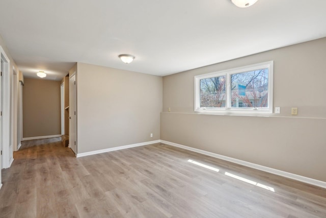 spare room featuring baseboards and light wood-type flooring