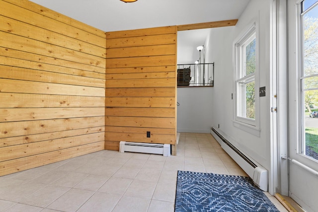 empty room featuring wood walls, a baseboard heating unit, and light tile patterned floors