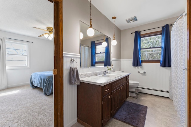 full bathroom featuring visible vents, a healthy amount of sunlight, a wainscoted wall, and a baseboard radiator