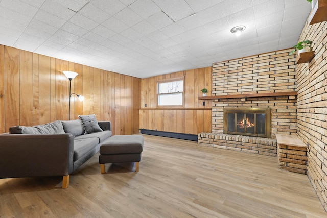 living room with a fireplace, a baseboard heating unit, wood walls, and wood finished floors