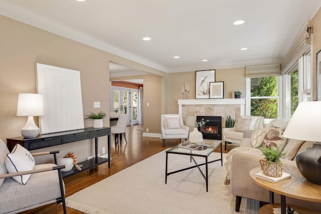 living room featuring a tiled fireplace, baseboards, recessed lighting, and wood finished floors
