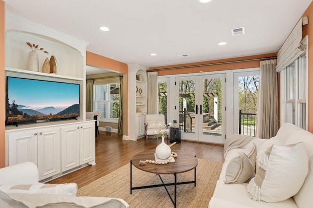 living room featuring a healthy amount of sunlight, french doors, visible vents, light wood-type flooring, and recessed lighting