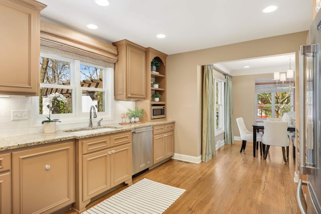 kitchen with baseboards, a sink, backsplash, a wealth of natural light, and stainless steel appliances