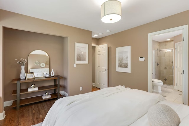 bedroom featuring baseboards, wood finished floors, and connected bathroom