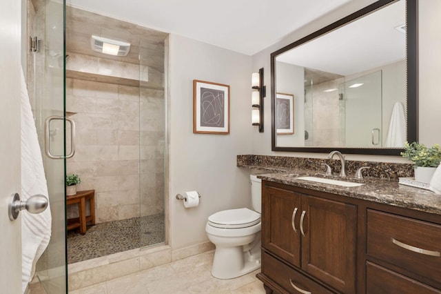 bathroom featuring vanity, baseboards, a stall shower, and toilet