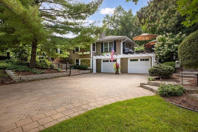 view of front of house featuring decorative driveway, a chimney, and a garage