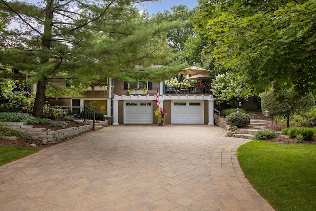 view of front of home featuring stairway, decorative driveway, a balcony, and a garage