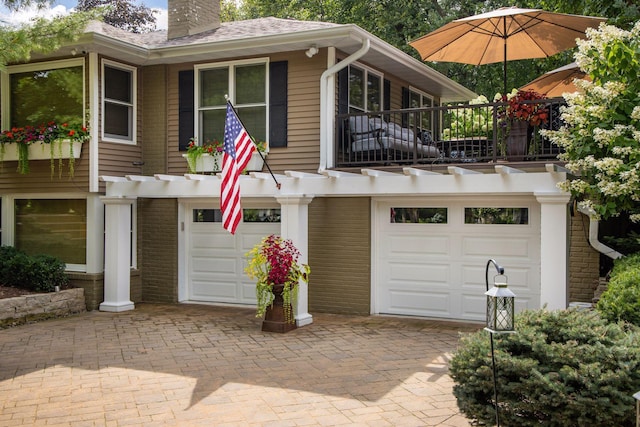 view of front of home featuring an attached garage, decorative driveway, and a chimney