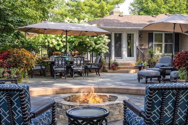 view of patio / terrace with a fire pit, outdoor dining area, and entry steps