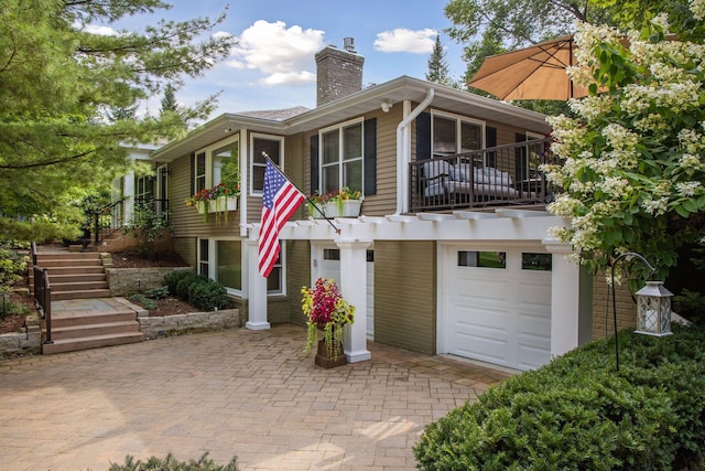 view of front of house with stairway, a chimney, a balcony, and a garage