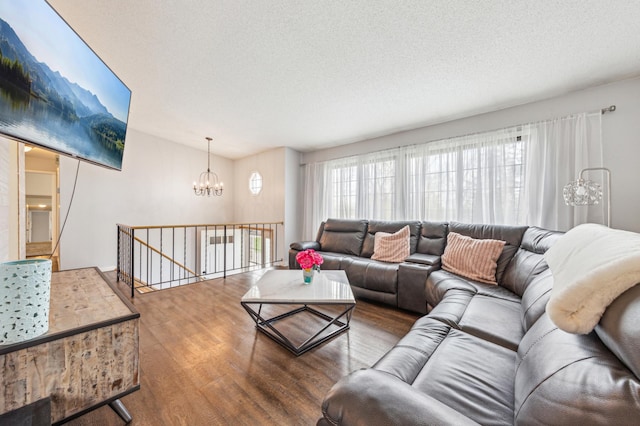 living room with a textured ceiling, a wealth of natural light, wood finished floors, and a notable chandelier