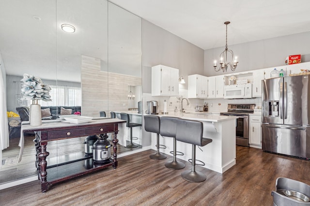 kitchen featuring white cabinets, appliances with stainless steel finishes, light countertops, dark wood-type flooring, and backsplash