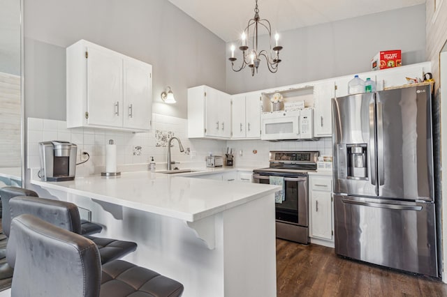kitchen featuring appliances with stainless steel finishes, a sink, light countertops, a peninsula, and backsplash