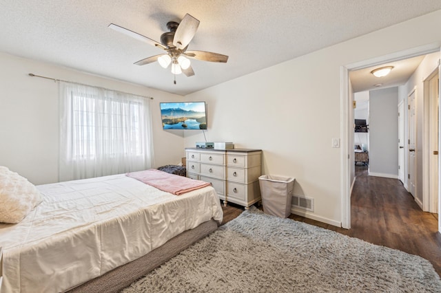 bedroom featuring a textured ceiling, a ceiling fan, baseboards, wood finished floors, and visible vents