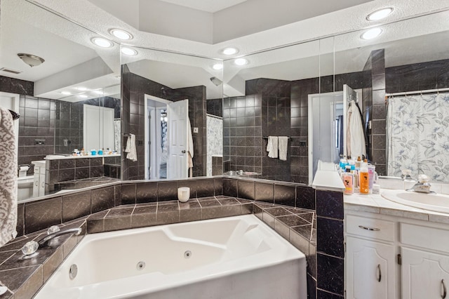 bathroom featuring recessed lighting, tile walls, a tub with jets, and vanity