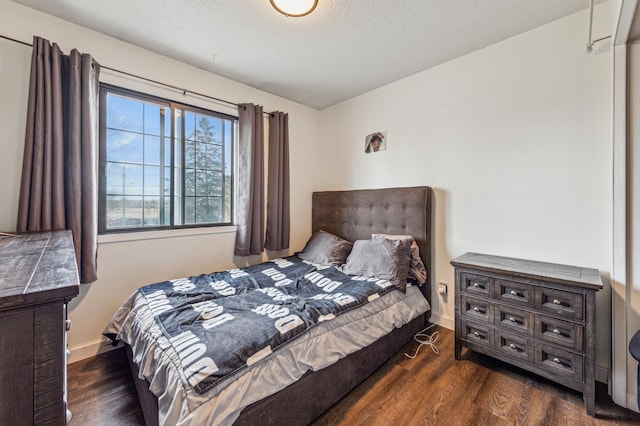bedroom featuring baseboards, a textured ceiling, and wood finished floors